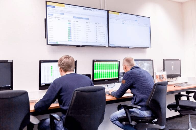Two people working at screens in a control room